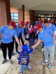Baseball players greet student coming in to the Early Learning Center