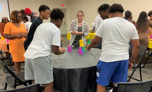 Students at a table playing a game, stacking cups