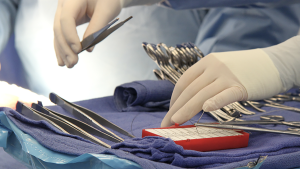Gloved hands working with medical tools on a tray