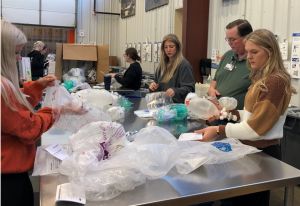 Radiographer students packing items at a table and getting instruction from Mission Outreach employee