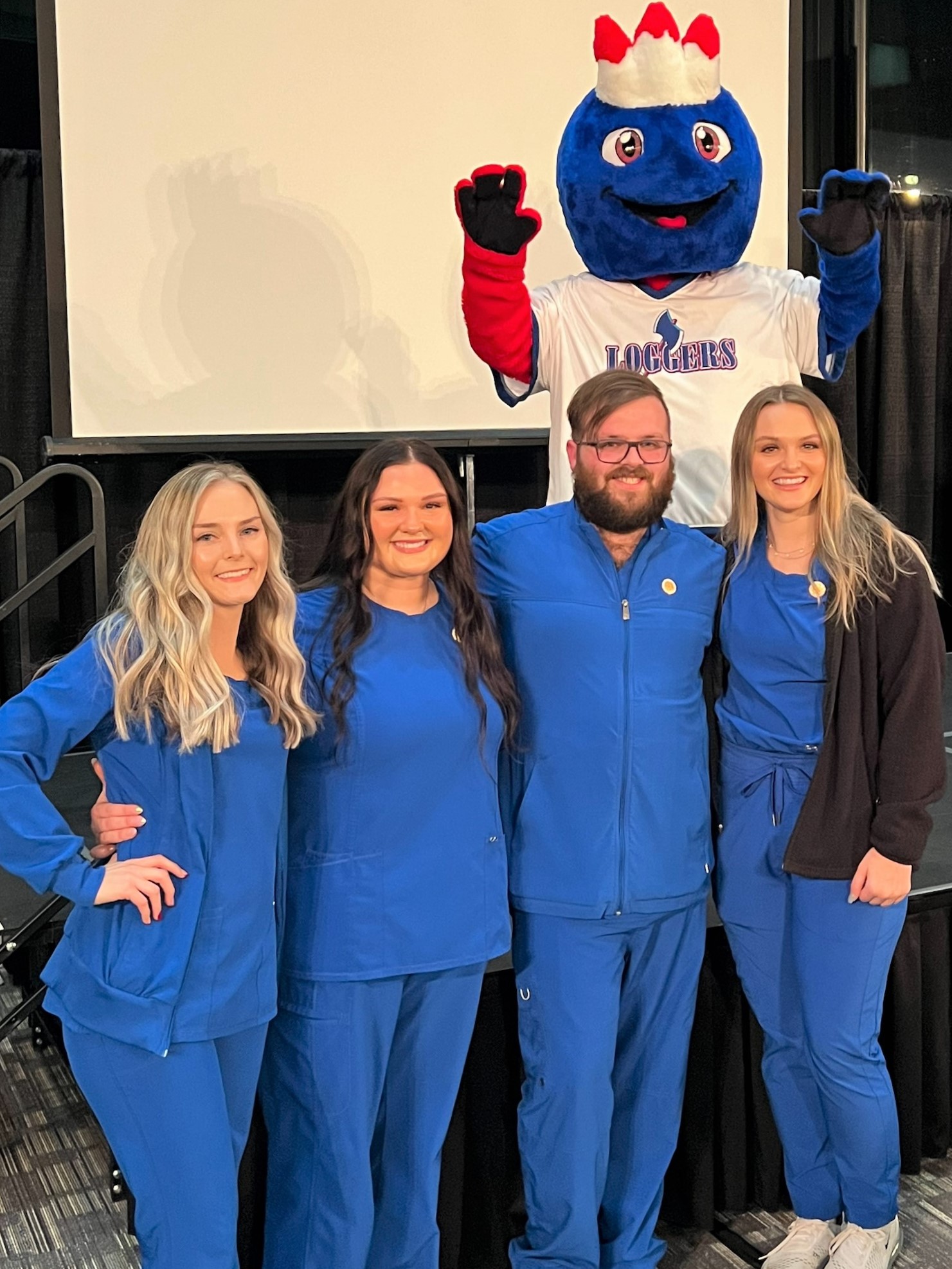 Four nursing graduates with college mascot Linc