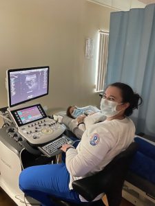 One student using sonography equipment to scan another