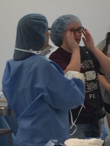 Janice Lovekamp providing surgical technology head cover and mask to a student.
