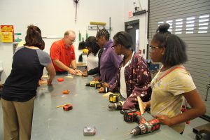 Bill Harmon and Holly Bauman working with Career Launch teens on wood peg game project