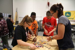 Holly Bauman working with Career Launch teens on wood peg game project