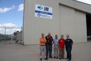 Dave Pietrzak, Arnold Tullis, Todd Cole, Rick Stillman and Christina Courier in front of new sign at aviation center