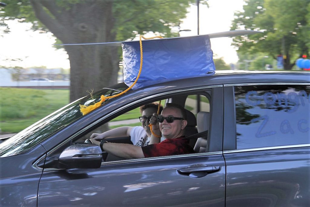 large grad cap on top of car in parade