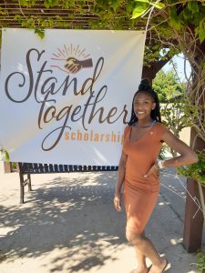 Kylana Moore next to Stand Together Scholarship sign