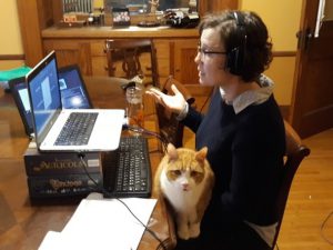 Andrea Echelberger sitting with her cat at a laptop in her dining room