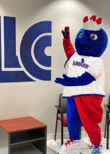 Linc gesturing toward LLCC logo on the wall