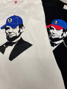 While and black T-shirts with Abe Lincoln wearing an LLCC cap
