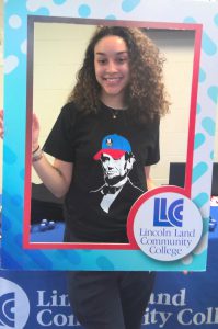 Lanphier student wearing an LLCC Abe T-shirt and holding an LLCC frame