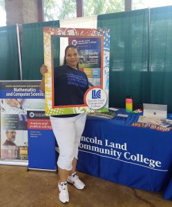 Ericka White, LLCC alum and state director at Illinois SBDC Network with Department of Commerce and Economic Opportunity, stops by LLCC table for a picture with the LLCC frame