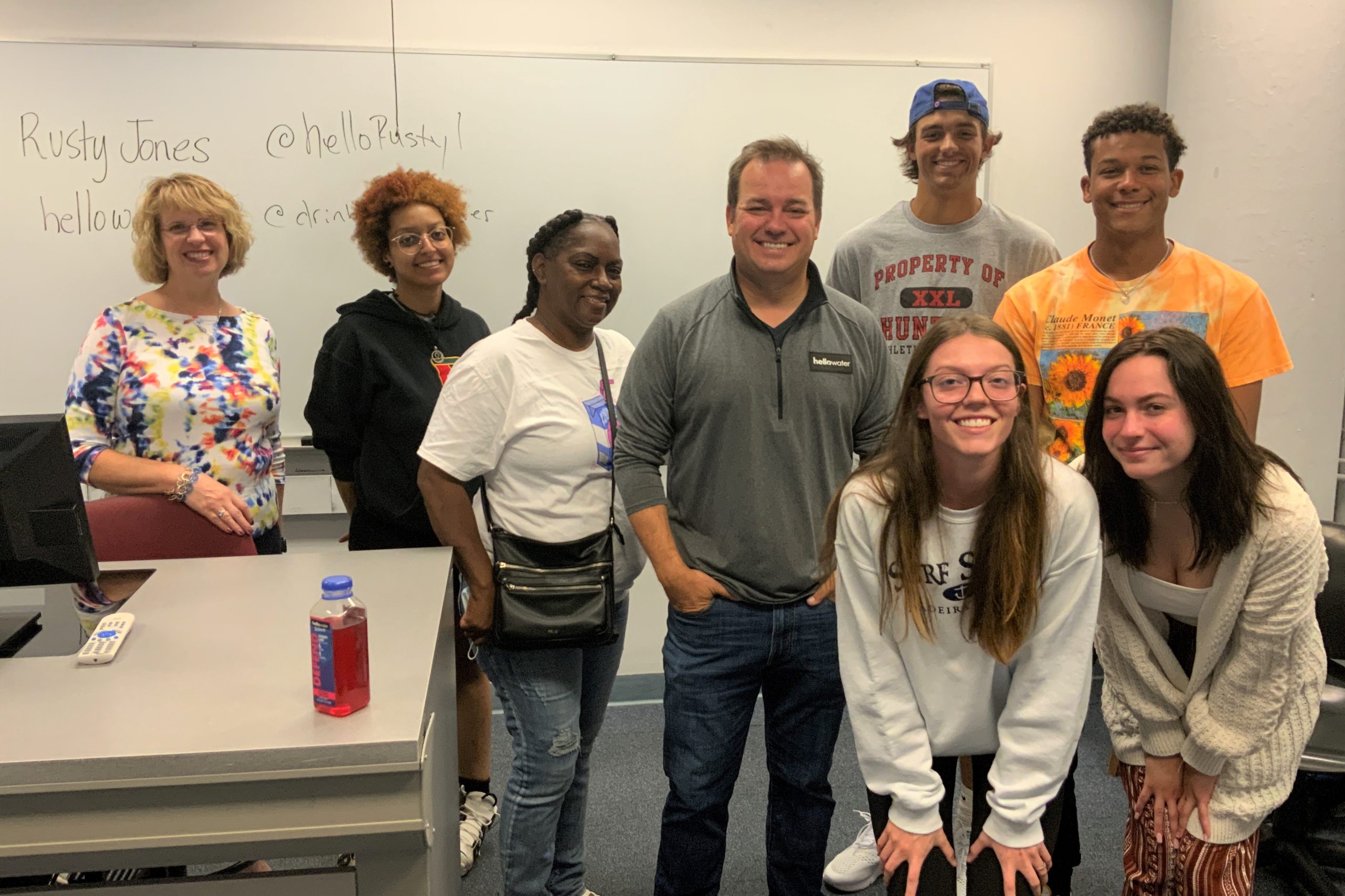 Christie Hovey and students in her business class pose for a photo with Rusty Jones at the front of a classroom.