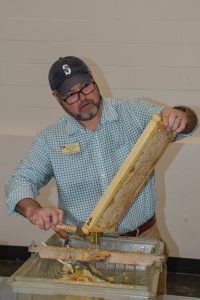 Brent Todd scraping honey off of comb