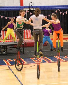 Three circus members on unicycles