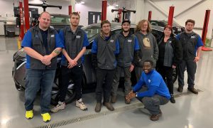 Eight auto tech students standing in front of car