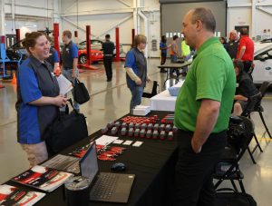 Foreground: student talking to employer. Background: students visiting other employer exhibits.