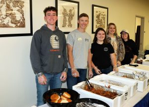 Five LLCC Ag Club students lined up behind the serving table