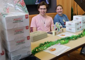 Two students at table in A. Lincoln Commons selling boxes of Krispy Kreme donuts