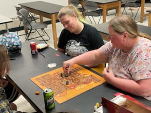 Lucinda Caughey playing board game with students