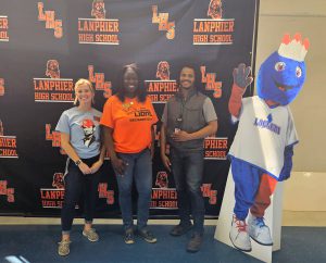 Mackenzie Bryant, Kim Wilson and Brandon Lewis standing with Linc in front of Lanphier backdrop