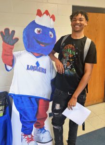 Student standing with arm on cardboard cutout of Linc