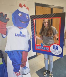 Student holding Loggers picture frame and standing next to Linc