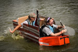 TRIO staff paddling in a cardboard boat.