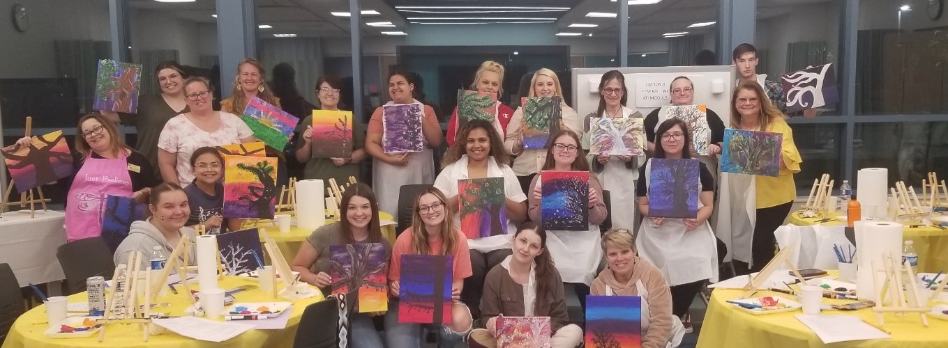 Attendees holding up their finished paintings