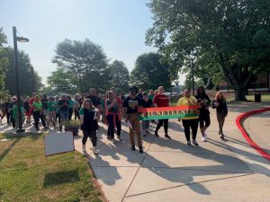 Faculty, staff, students and community members walking in Freedom Walk, led by staff holding a Juneteenth banner