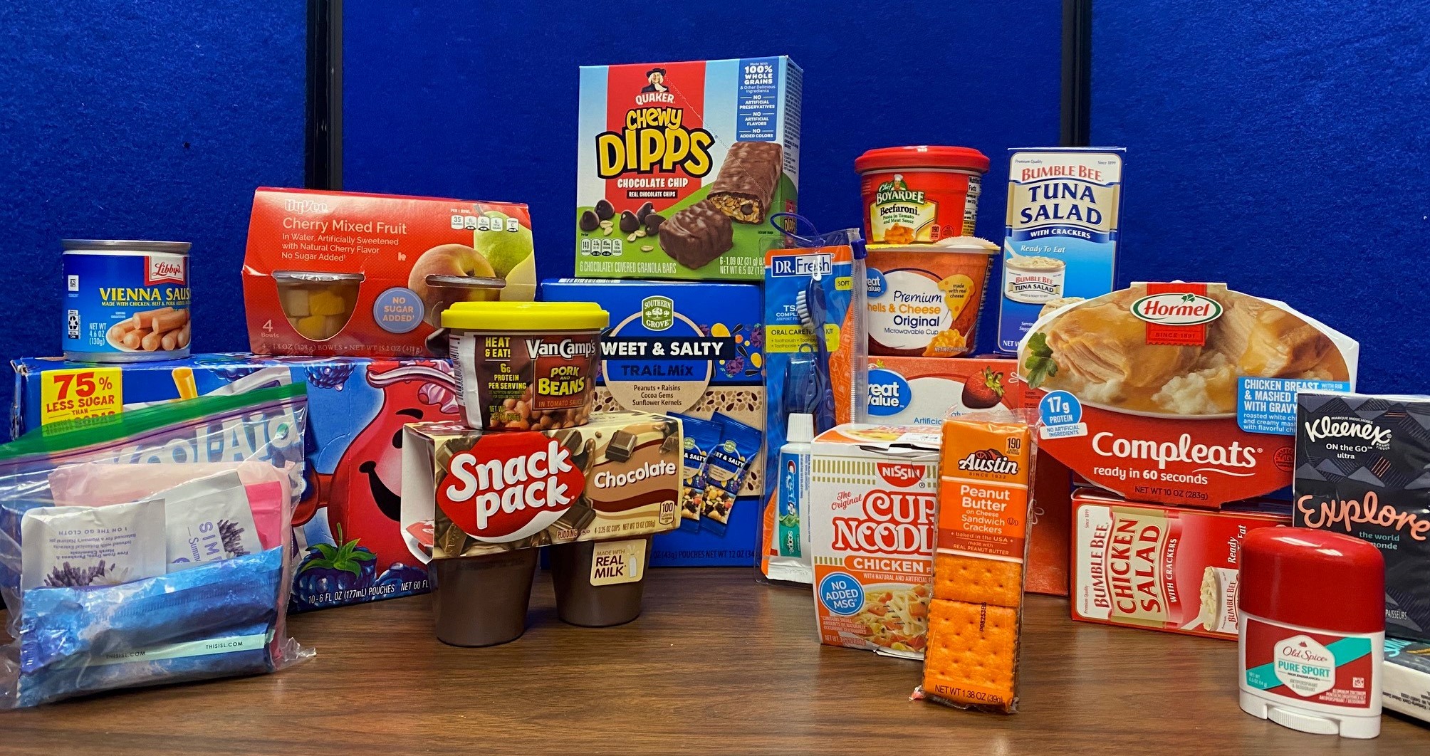 A photo of some of the popular items in the pantry including Vienna sausages, Snackpack pudding cups, chewy granola bars, tuna and chicken salad kits, kleenex, deodorant, toothpaste and toothbrush.