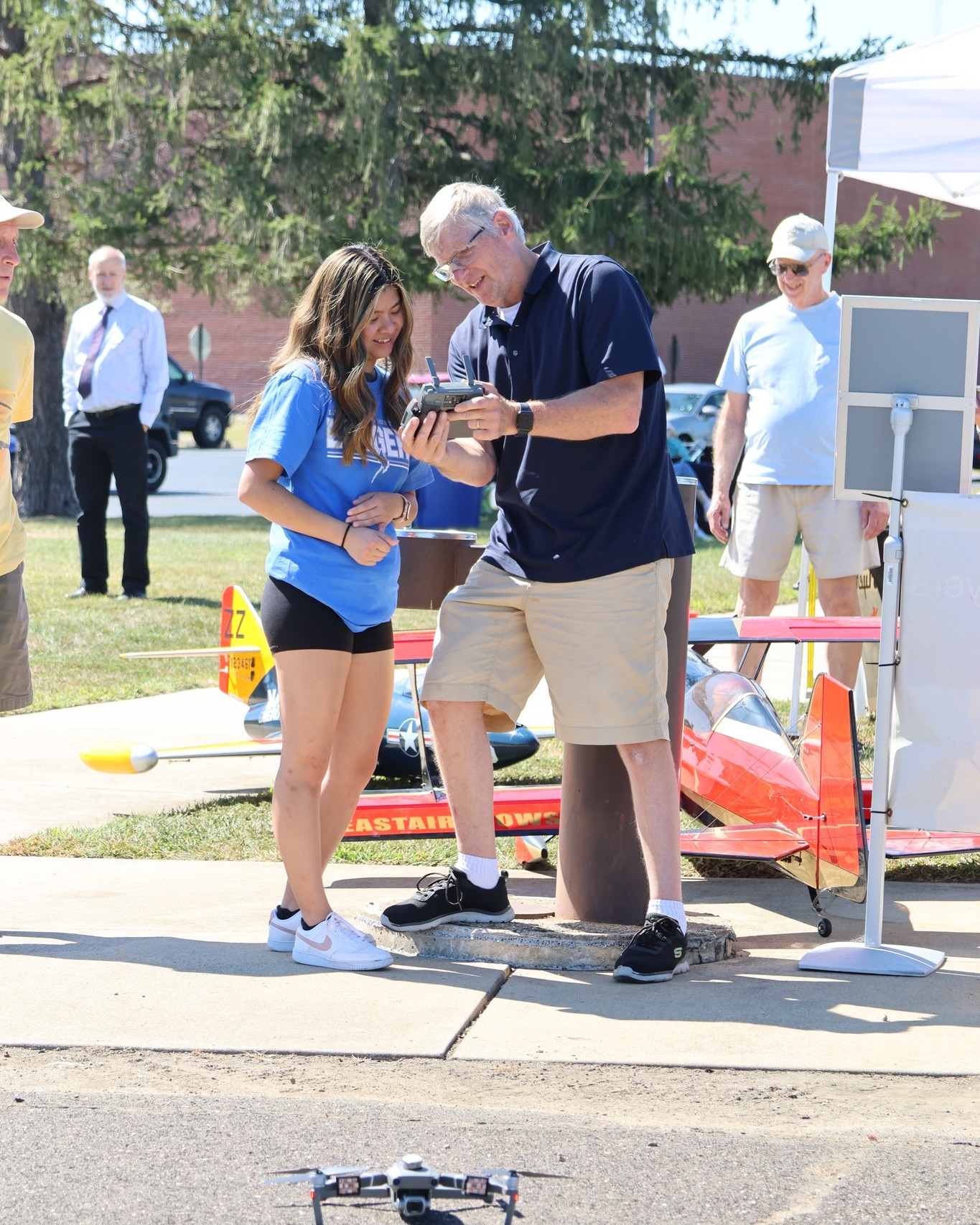 A young woman looking at a drone remote control held by a man outside