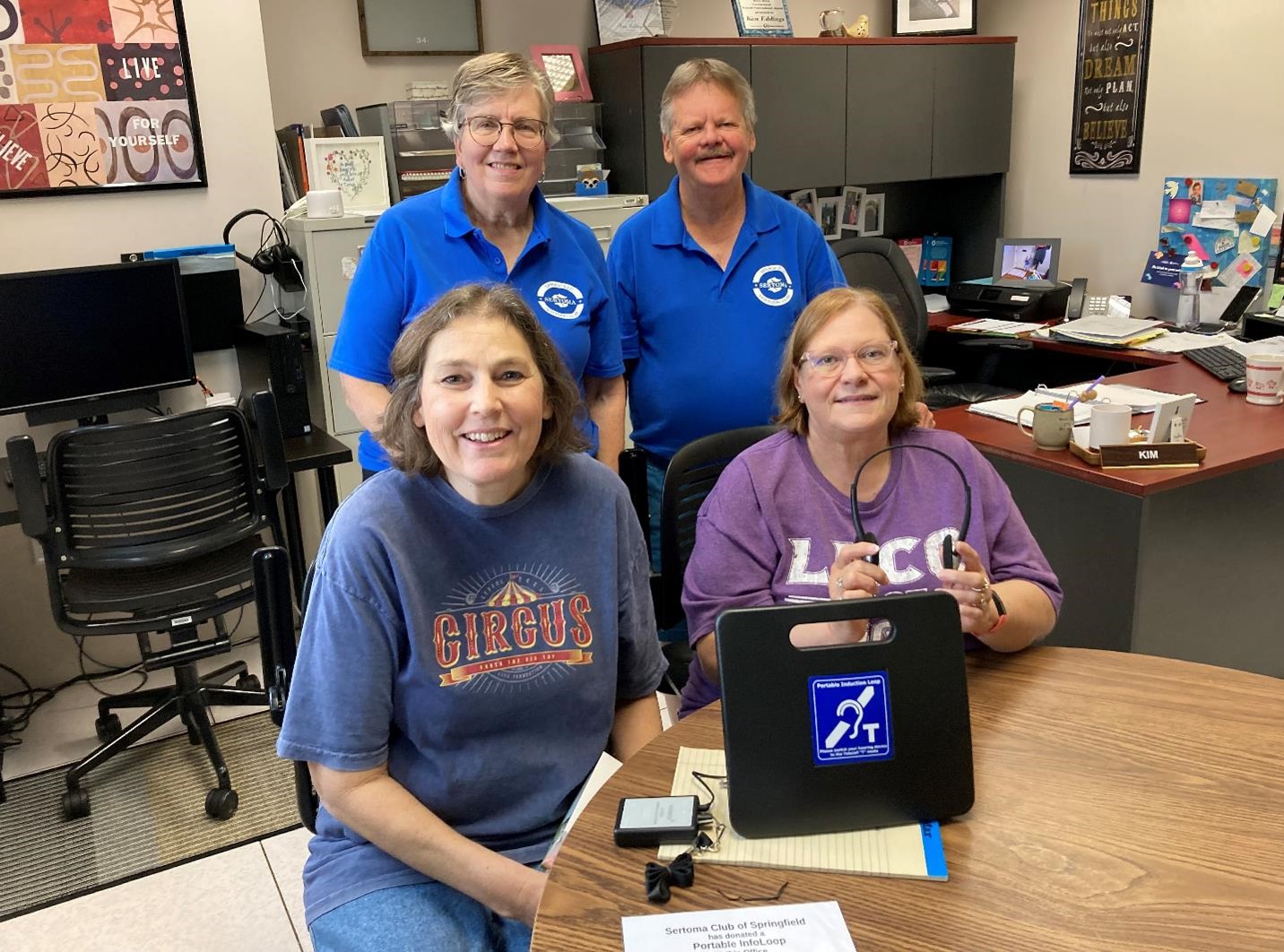 Photo: (seated) Kim Eddings and Elaine Higgason of Accessibility Services; accept the donation of a Portable InfoLoop device from members of the Sertoma Club of Springfield (back) Cheryl Pence and Keith Baker.