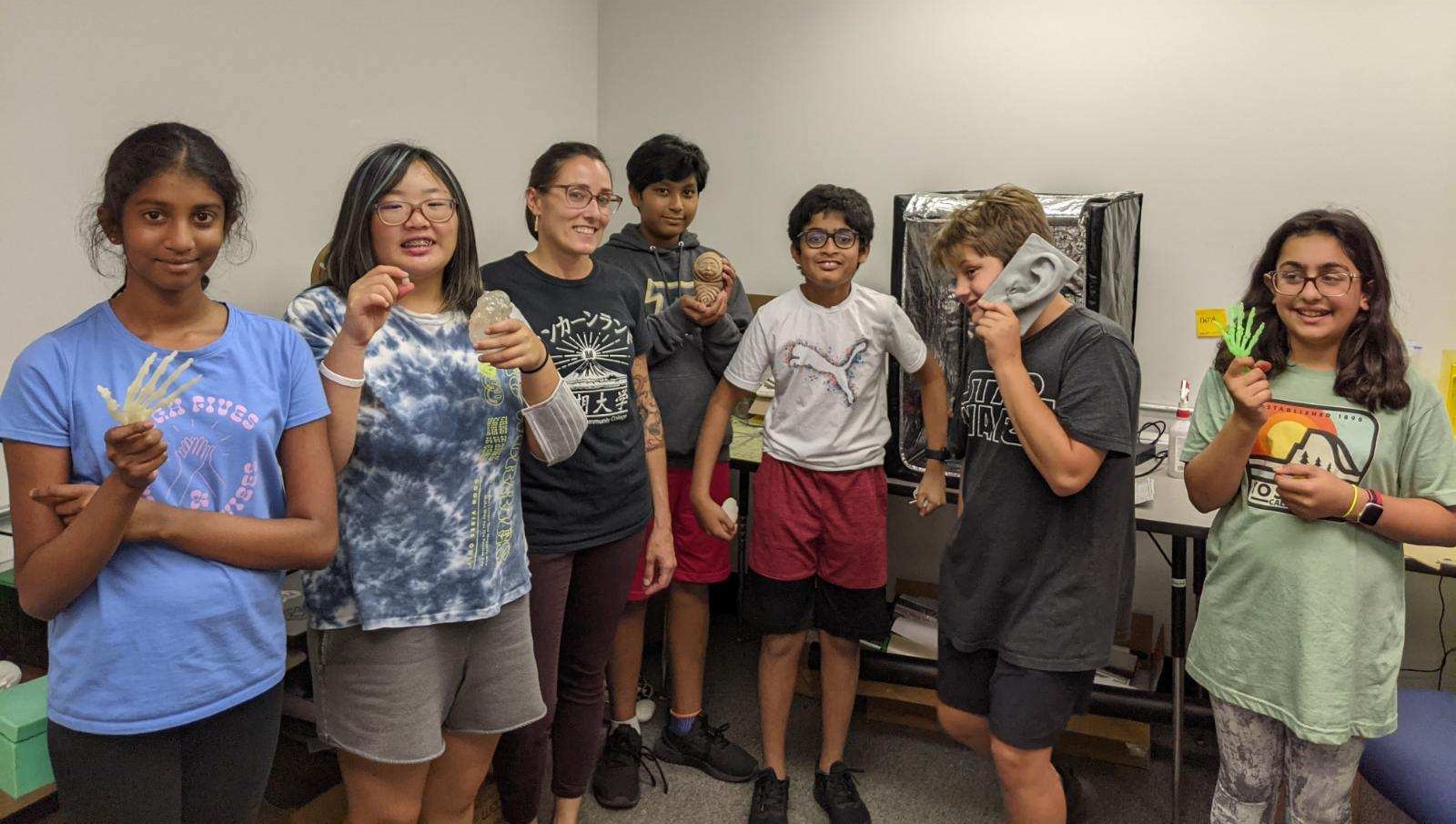 group of middle school aged children holding 3D-printed objects in the LLCC Arts and Communication Fab Lab