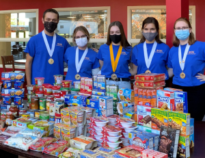 Five PTK students standing with food collected for Operation Full Belly