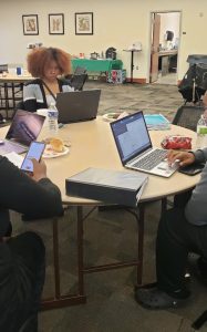 Three students working on laptops at a study table