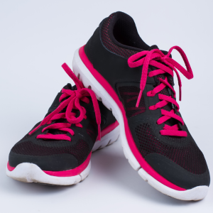 Black tennis shoes with pink shoelaces on a white background.