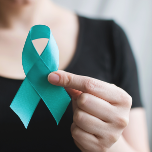 A woman holding a teal ribbon for Sexual Assault Awareness Month.
