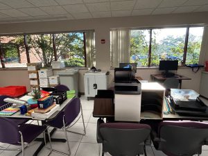 Office room cluttered with boxes, books and misc. items.