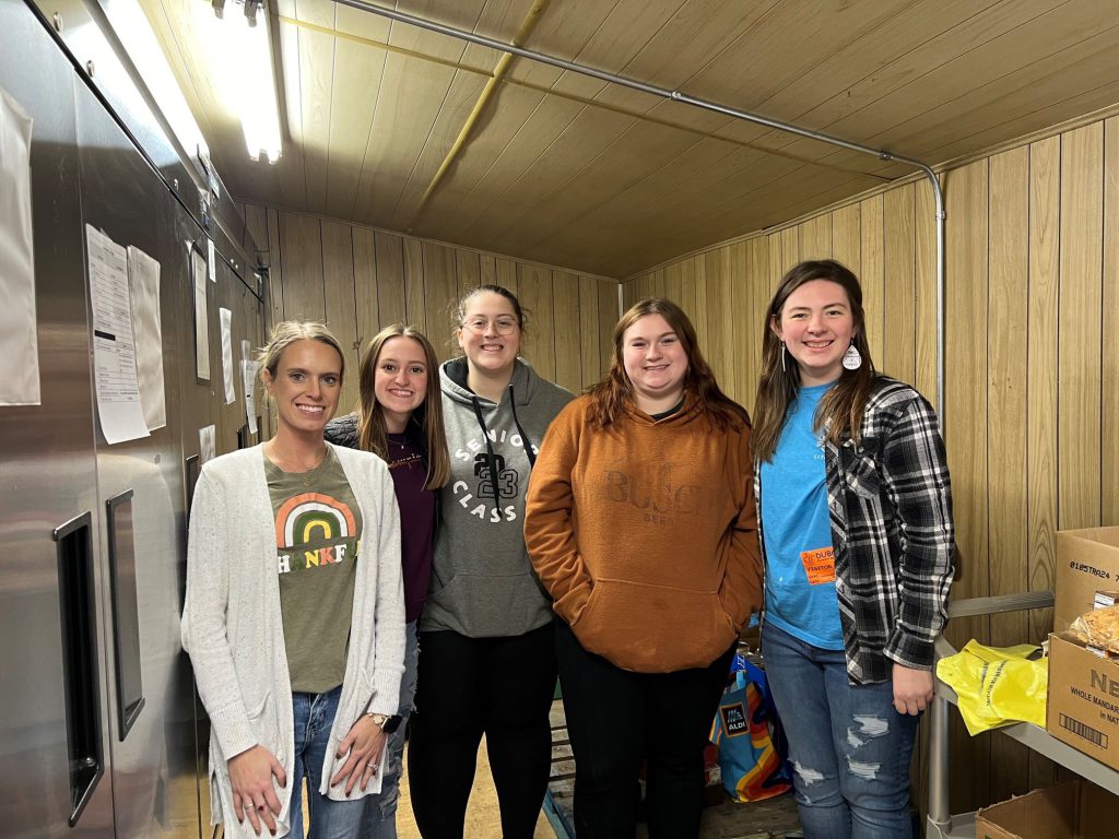 students smiling at a food drive.