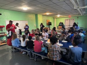 Students in the Boys and Girls Club sitting at a table during a cooking demonstration.