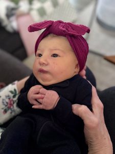 newborn baby in a black blanket and burgandy headband.